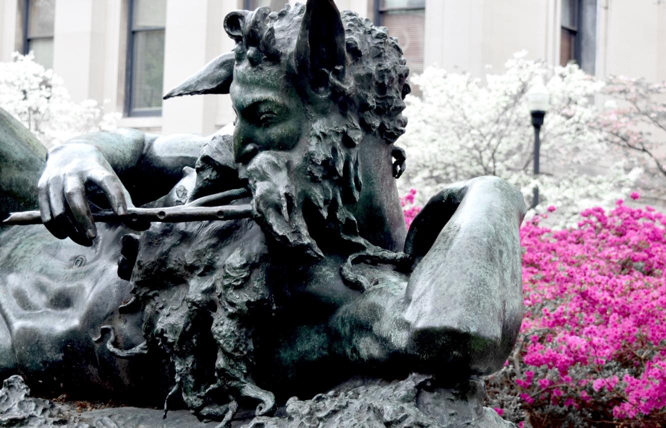 Pan statue with shrubs in bloom